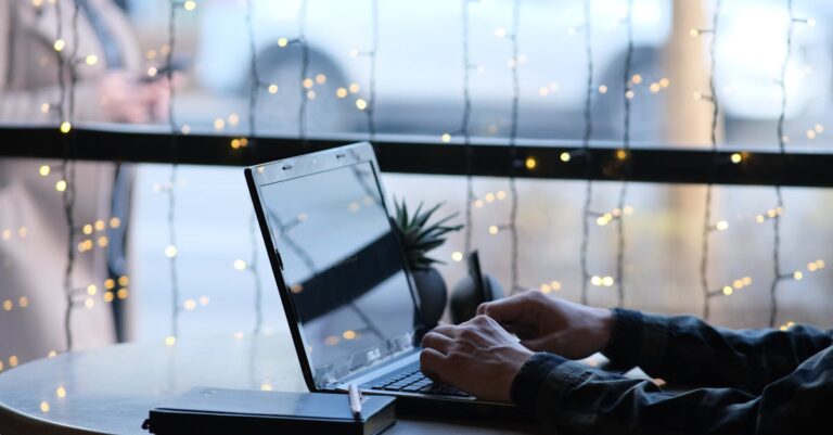 Laptop com rascunho de e-mail e caderno de agenda, mãos digitando um pedido de reunião objetivo