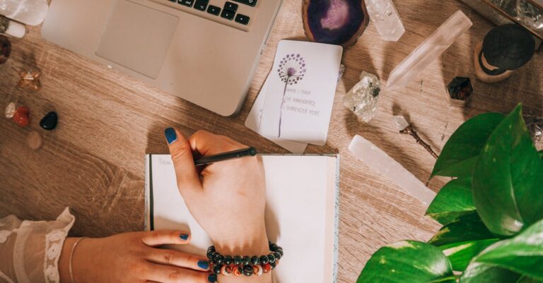 Mãos próximas a laptop com texto editado e caderno com anotações sobre uso de ferramentas digitais