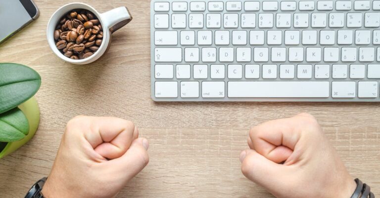 Pessoa digitando manuscrito no laptop com páginas impressas e checklist ao lado, preparando declaração de uso de IA.