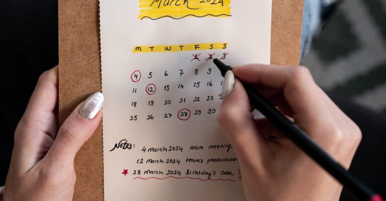 Calendário marcado com prazos e lembretes ao lado de laptop e caneta, foco em organização de datas.