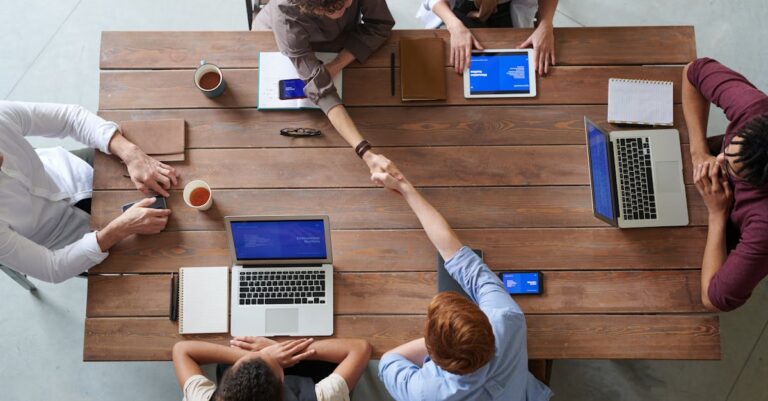 Pequeno grupo com cadernos e canecas ao redor de mesa, trocando anotações em sessão de responsabilização