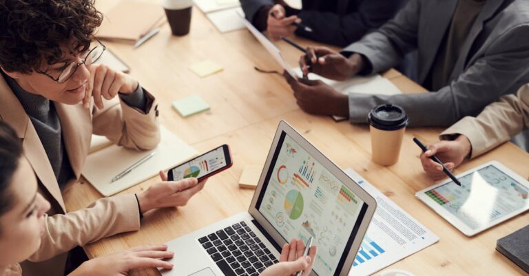 Equipe consultando resultado estatístico no laptop e discutindo em mesa de escritório