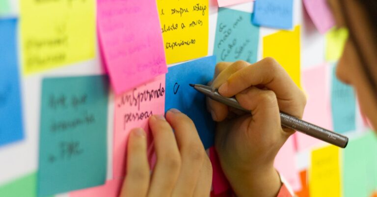 Mesa com mapa, post-its e mãos apontando parceiros, representando mapeamento de conexões institucionais.