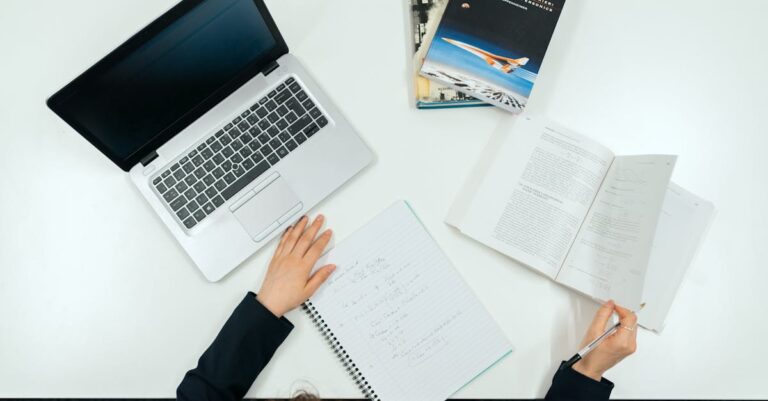 Mesa com artigos acadêmicos, navegador aberto e marcadores, cenário de busca bibliográfica
