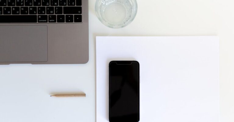 Smartphone virado para baixo junto a laptop e fones, sugerindo redução de notificações e foco.