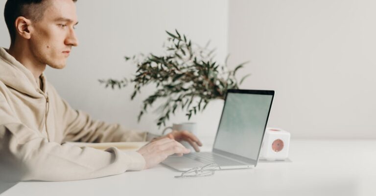 Mãos checando portal do programa em laptop, com notificações e calendário visíveis para acompanhar prazos.