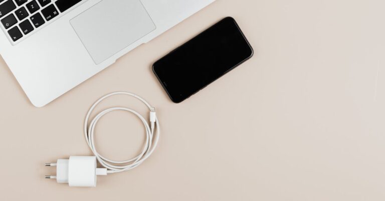 Mesa com laptop, smartphone, fones e cabos, tela mostrando teste técnico antes da prova.