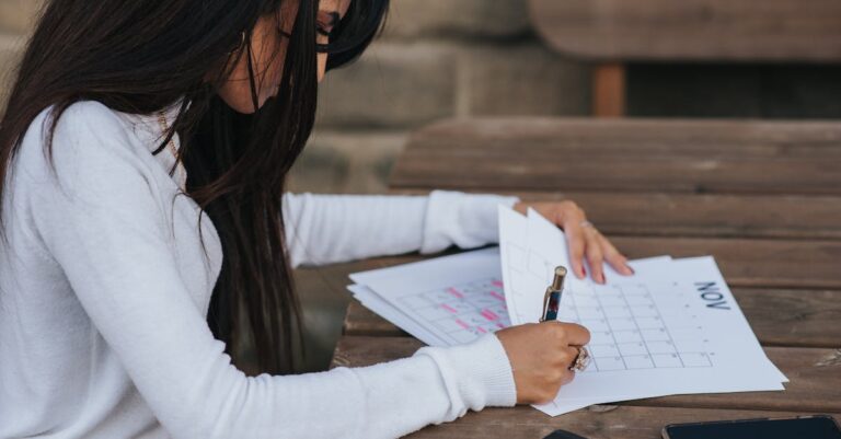 Planner de papel ao lado de smartphone e caneta sobre mesa, comparando solução analógica e digital.