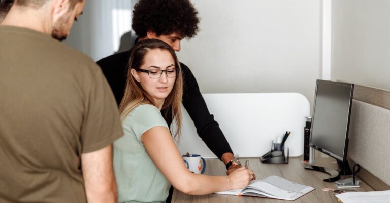 Laptop com página de bolsas aberta, passaporte e mapa ao lado sobre a mesa