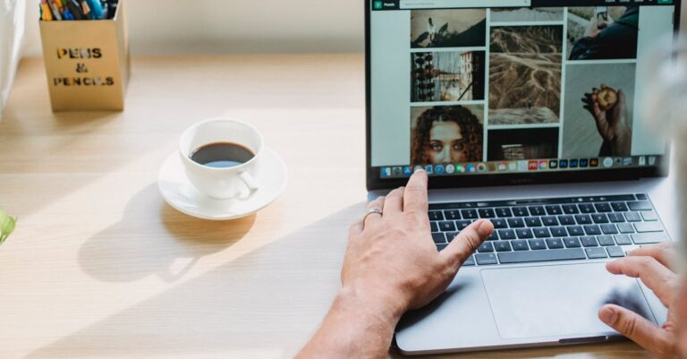 Laptop com site institucional desfocado na tela e mãos ao teclado em mesa de escritório