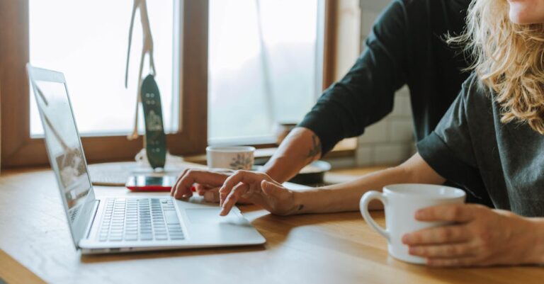 Mãos configurando laptop com checklist e notas em caderno sobre mesa