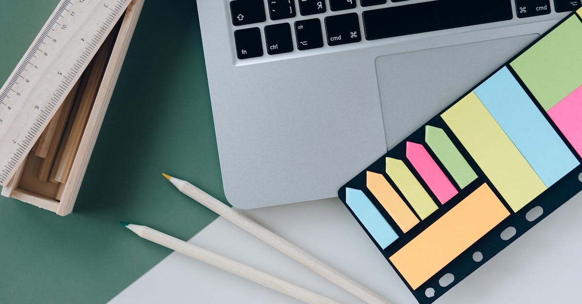 Mesa de trabalho com laptop, cadernos e rascunhos de pré‑projeto, mãos digitando e anotações visíveis