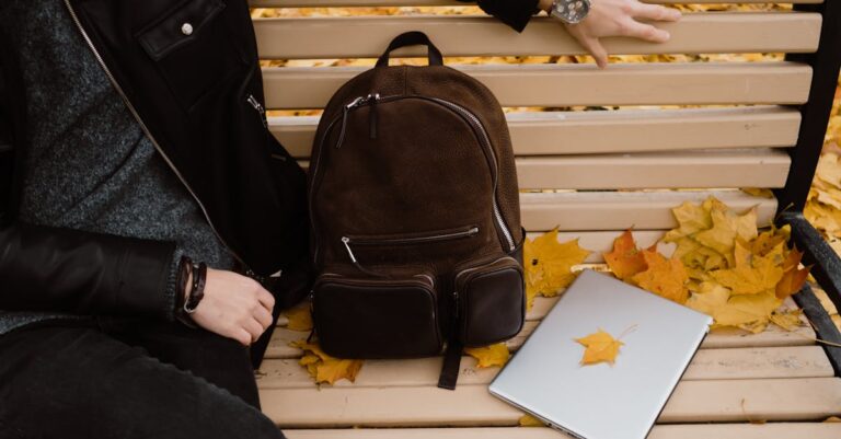 Mãos digitando em laptop com mochila e documentos ao redor, simbolizando busca por serviços de apoio na universidade.