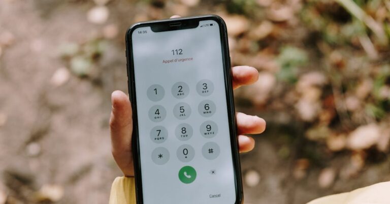 Mão segurando smartphone com a tela de emergência desfocada, simbolizando busca de ajuda imediata.