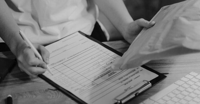 Documentos e formulários de auxílio estudantil dispostos em mesa, prontos para solicitação