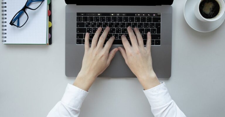 mãos preenchendo planilha de revisão de referências ao lado de um laptop