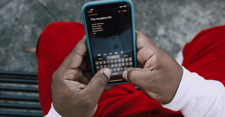 Mãos digitando e-mail no notebook com smartphone e anotações ao lado