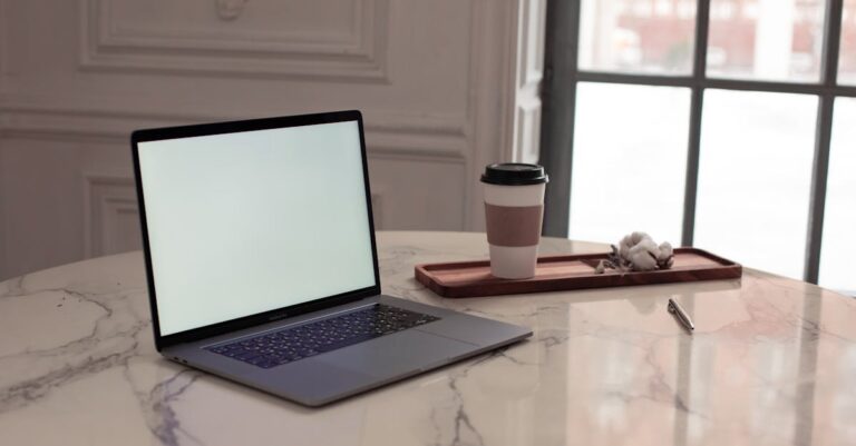 Planilha aberta no laptop com gráficos simples, caneta e café sobre mesa