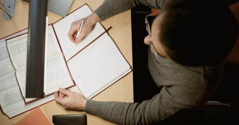 Mãos organizando CV, projeto e notas sobre mesa, simbolizando preparação para mestrado