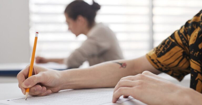Manuais e notas sobre a mesa, folheto institucional em mãos com ambiente acadêmico desfocado