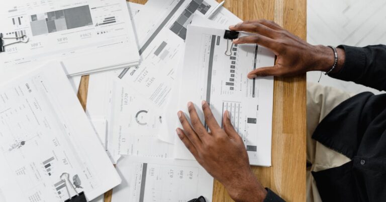 Mãos apontando para relatórios e gráficos sobre mesa em escritório institucional