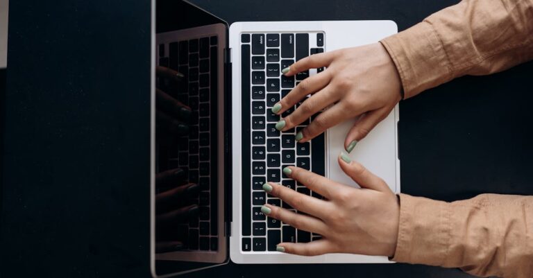 Computador exibindo dashboard com métricas e gráficos ao lado de caderno e tabelas impressas