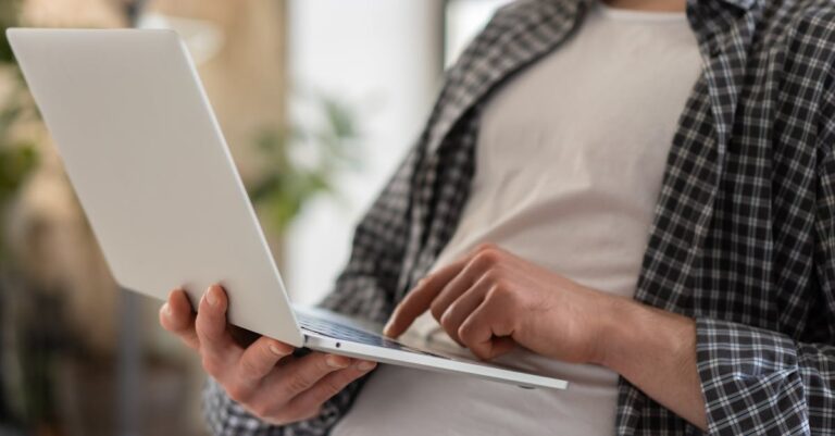 Mãos digitando prompts no laptop, notas com termos técnicos ao lado, preparo de prompts