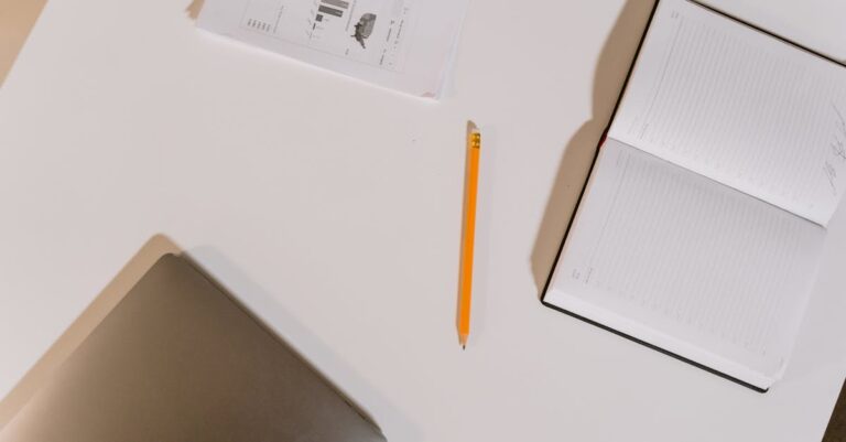 Mesa com caderno aberto, pilha de páginas, cronômetro e checklist, sugerindo passadas escalonadas.