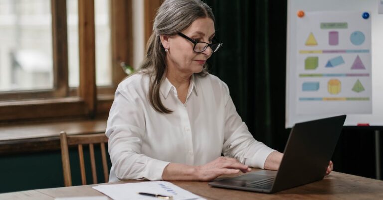 Laptop com gerenciador de referências aberto e caderno ao lado, vista de cima