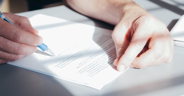 Mãos assinando requerimento acadêmico sobre mesa com prancheta e documentos