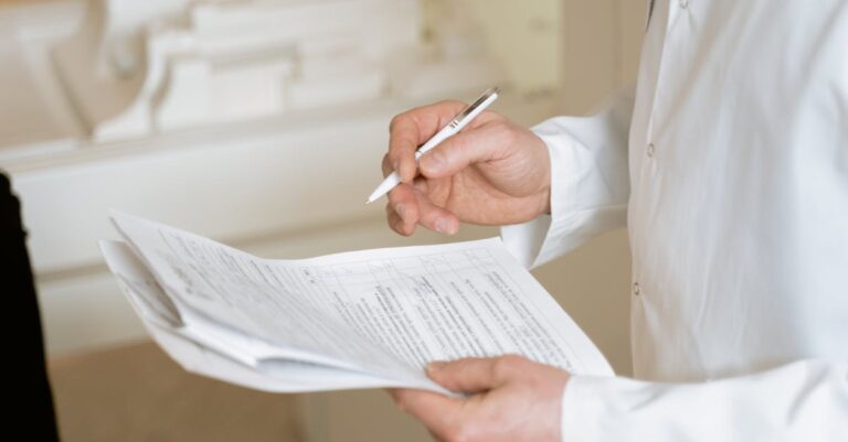 Mãos segurando formulário de encaminhamento em consultório, prancheta e iluminação suave