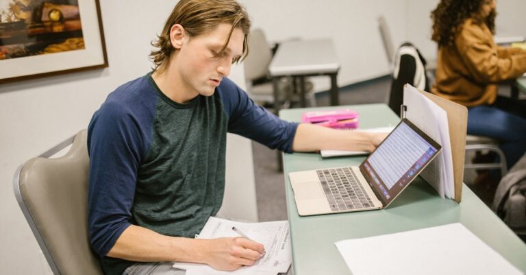 Manual universitário e laptop sobre mesa com páginas de diretrizes, evidenciando consulta a normas