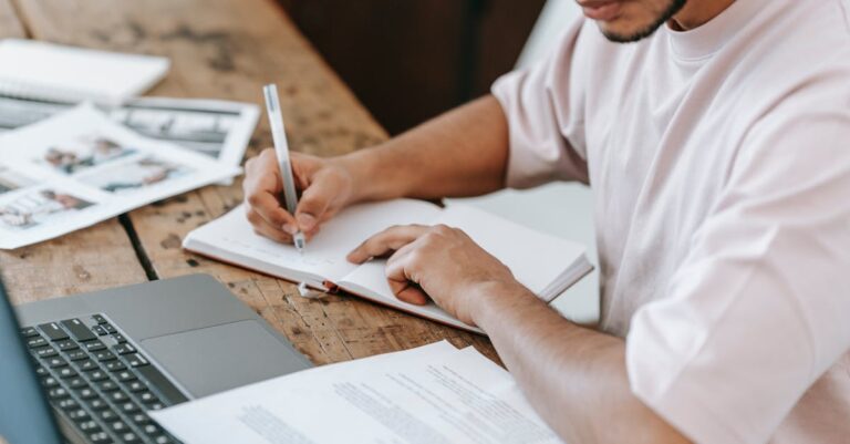 Laptop com página de periódico acadêmico desfocada, notas e café na mesa