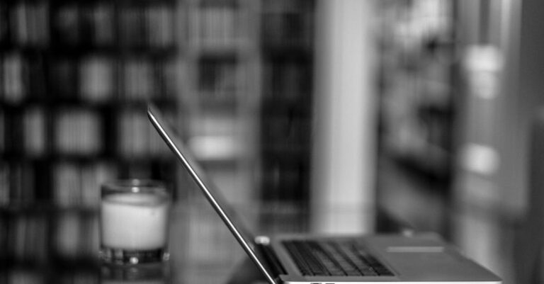 Laptop ao lado de disco externo com rack de servidores desfocado ao fundo, simbolizando opções local e nuvem
