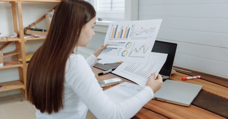 Pesquisador avaliando gráficos e planilhas no laptop, foco em revisão estatística e validação de resultados.