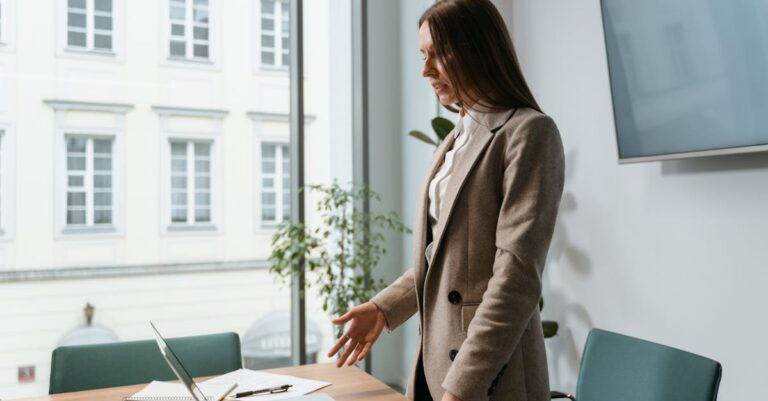 Candidata ensaiando apresentação oral com laptop e notas, preparando defesa e prova de inglês.