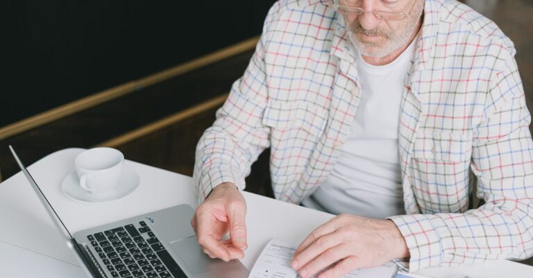 Mãos segurando fichas com perguntas, laptop e cronômetro em mesa, treino de defesa