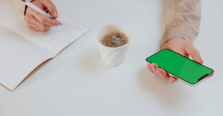 Mãos segurando smartphone com instruções e laptop com anotações sobre prompts, representando treino de prompts.