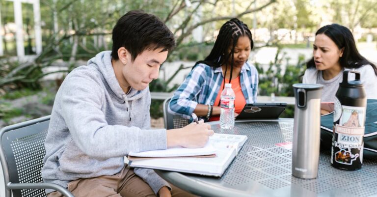 Pequeno grupo em mesa com laptops e artigos discutindo estratégias para integrar IA em pós-graduação.