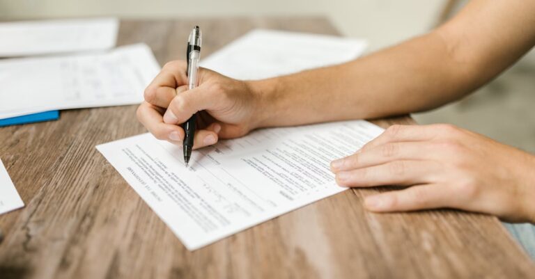 Mãos assinando um modelo de declaração impresso sobre mesa de escritório, com pasta e caneta ao lado
