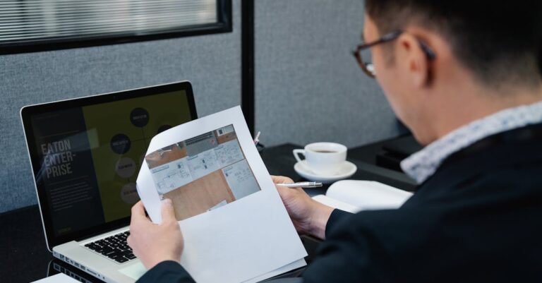 Pesquisador revisa código e documentação de versões no laptop em mesa de trabalho.