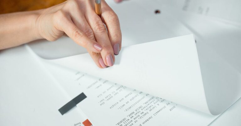 Mãos entregando manuscrito sobre mesa com cronômetro e papéis organizados, mostrando aceleração do processo