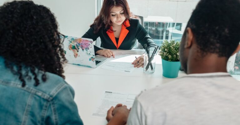 Mãos apontando para contrato e rascunhos sobre a mesa, sugerindo negociação de entregas com orientador.