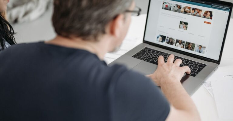 Tela de laptop com portal de bolsas aberto, mãos no teclado e materiais ao redor