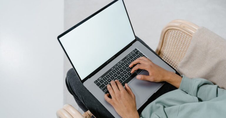 Tela de laptop com gráficos e planilha, mãos apontando para métricas de bem‑estar e rendimento