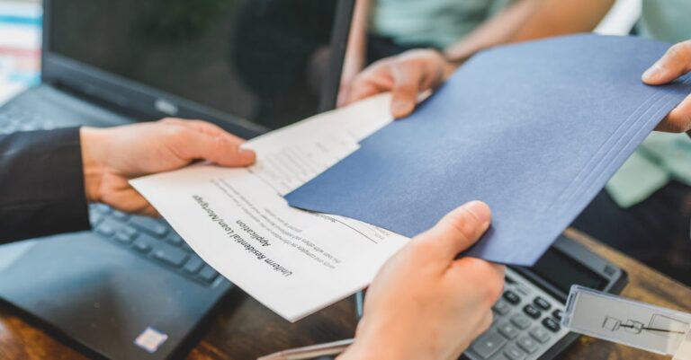 Mãos sobre contrato e calculadora, com laptop e documentos na mesa simulando avaliação financeira entre opções.