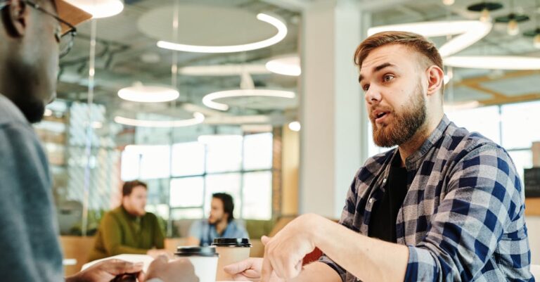 Duas pessoas discutindo manuscrito com gráficos e anotações espalhadas sobre a mesa