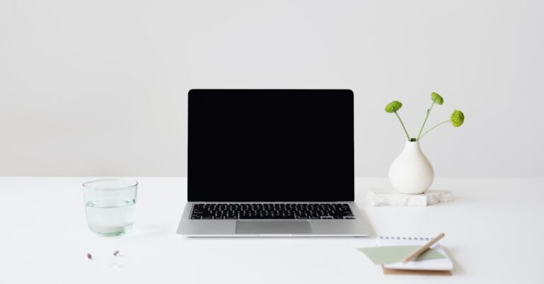 Fluxo de trabalho de pesquisa no laptop, cadernos abertos, artigos impressos e esboços de fluxograma.