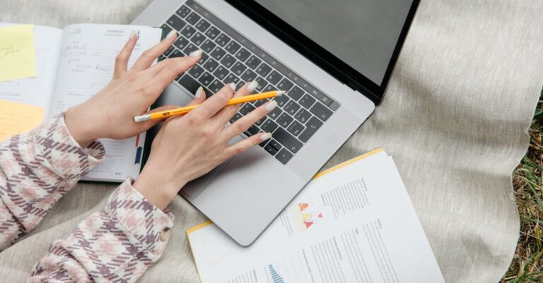 Mãos escrevendo rascunho de projeto com páginas anotadas e post‑its sobre mesa
