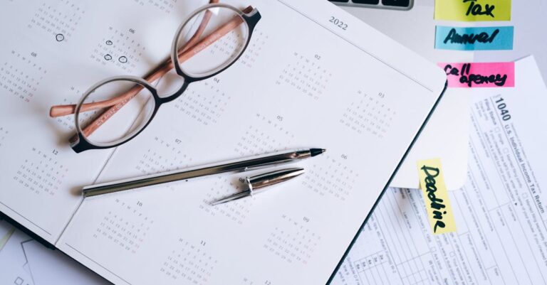 Laptop com documento de revisão aberto, calendário e anotações de prazos